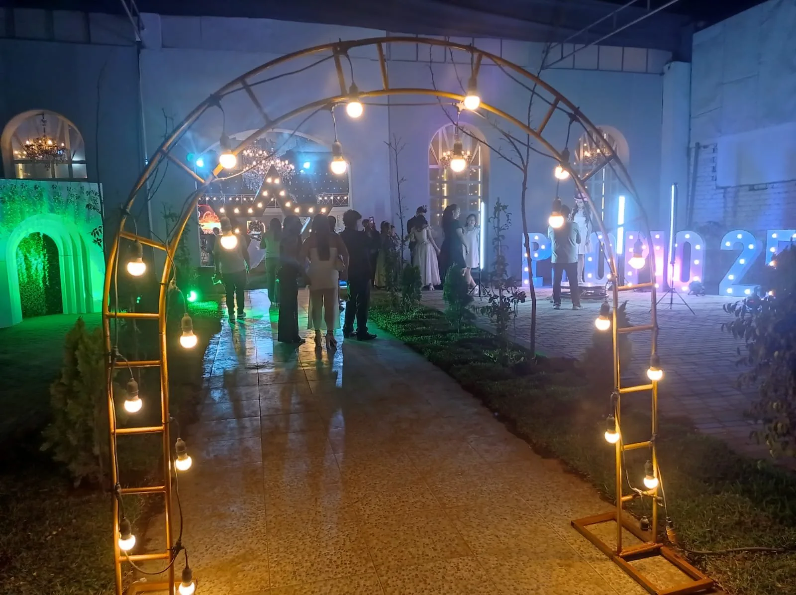 Patio de noche con arcos de bombillas y letras gigantes