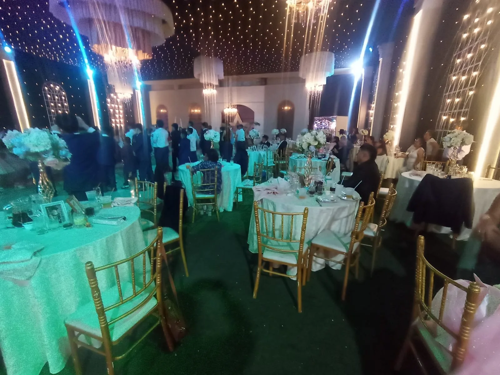 Mesas redondas con sillas chiavari doradas e iluminación de color