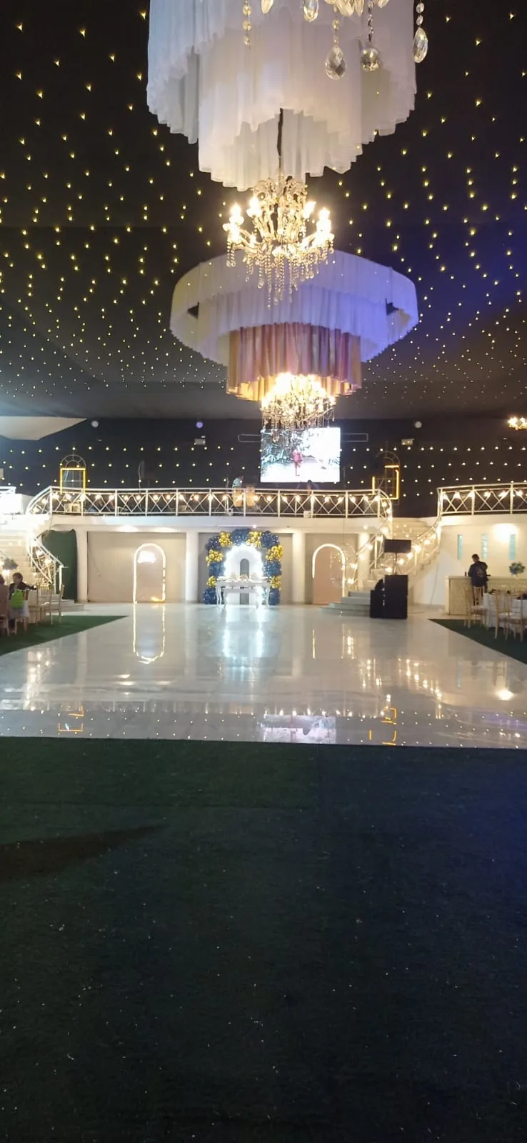 Salón interior con piso espejado, escaleras dobles y candelabros
